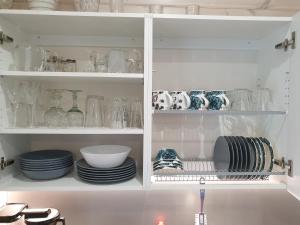 un armario blanco lleno de platos, tazones y vasos en Adeli Holiday Cottage Ellivuori, en Sastamala