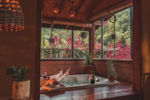 um homem numa banheira num quarto com uma janela em Casa Pedacinho de Céu com banheira de hidromassagem e lareira em São Bento do Sapucaí