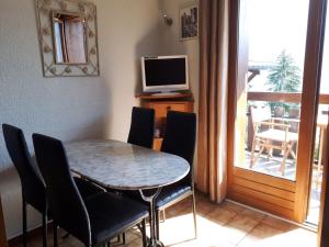 a dining room with a table and chairs and a television at Studio 2 personnes - vue Mont blanc in Saint-Gervais-les-Bains