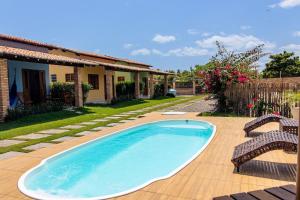 - une piscine avec 2 chaises et une maison dans l'établissement Condomínio aconchegante a 300mt da Praia de Barra Grande, à Barra Grande