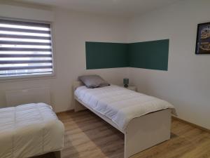 a room with two beds and a window and a bedvisor at Gîte l'harmonie I in Fraize