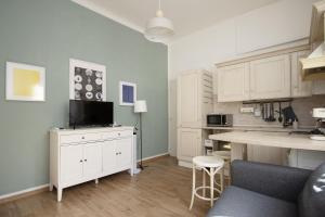 a kitchen with white cabinets and a table with a tv at Charme&Design in Milano in Milan