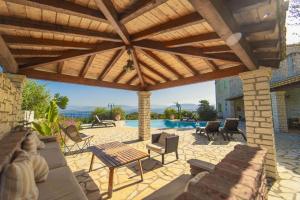 een patio met een houten pergola en een zwembad bij Villa Emily in Ágios Stéfanos