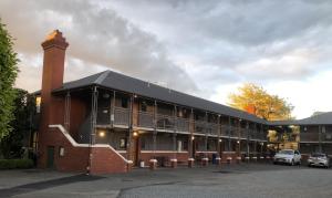 a large brick building with a chimney and a parking lot at Country Glen Lodge in Christchurch