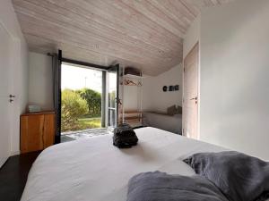 - une chambre avec un grand lit blanc et une grande fenêtre dans l'établissement Maison d'Hôtes Les Petites Terres, à Sainte-Marie de Ré