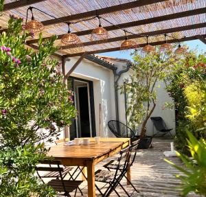 Une table et des chaises en bois sont disponibles sur la terrasse. dans l'établissement Maison d'Hôtes Les Petites Terres, à Sainte-Marie de Ré