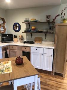 a kitchen with white cabinets and a wooden table at Leos Loft in Eugene