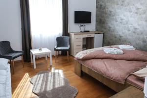 a bedroom with a bed and a desk and chairs at Cigándi Családi Panzió in Cigánd