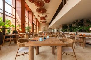 un restaurante con mesas de madera, sillas y plantas en Osh Hotel Getsemani en Cartagena de Indias