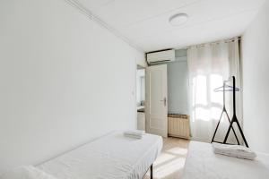 Camera bianca con letto e finestra di Barcelona Beach Vibes a Sant Adrià de Besòs