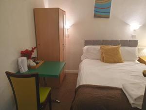 um quarto de hotel com uma cama e uma secretária verde em Ababeel Hotel em Birmingham
