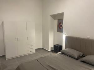 a white bedroom with a bed and a cabinet at Leo's Apartments in Koropíon