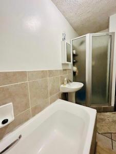 a bathroom with a shower and a tub and a sink at Makwande Self-Catering Apartment in Durban +5 photos