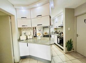 a kitchen with white cabinets and a counter top at Makwande Self-Catering Apartment in Durban