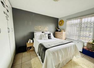 a bedroom with a white bed and a gray wall at Makwande Self-Catering Apartment in Durban