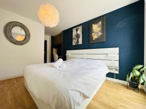 - une chambre avec un grand lit blanc et un mur bleu dans l'établissement Le vintage, à Tours
