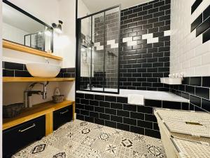 La salle de bains est pourvue d'un lavabo et d'une douche avec du carrelage noir. dans l'établissement Le vintage, à Tours