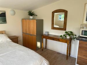 a bedroom with a bed and a desk and a mirror at Ferncroft Garden Studio in Histon