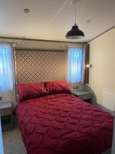 a red bed in a bedroom with two windows at Golden Palm Resort - The Atlas Family - Coastal Caravan Breaks in Chapel Saint Leonards +10 photos
