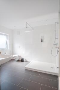 uma casa de banho branca com um chuveiro e um lavatório. em Neusaniertes 3Familienhaus am Bahnhof Wyhlen 7Min von Basel CH em Grenzach-Wyhlen