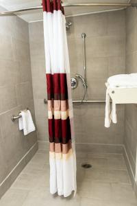 y baño con ducha y cortina de ducha roja y blanca. en Red Roof Inn Rochester - Henrietta, en Henrietta
