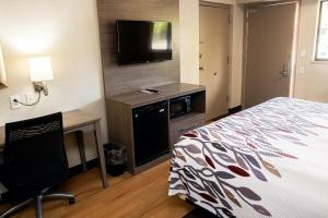 a hotel room with a bed and a flat screen tv at Red Roof Inn Rochester - Henrietta in Henrietta