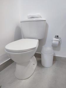 a white toilet in a bathroom with a roll of toilet paper at Habitación sencilla con baño privado Unicentro in Bogotá