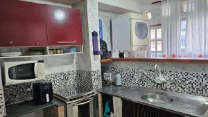 a kitchen with a sink and a microwave at Casa Will Maresias in Maresias