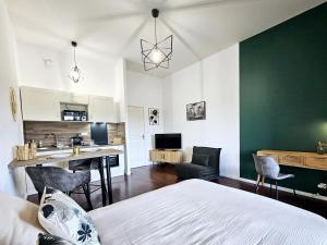 1 dormitorio con pared de acento verde y cocina en Octave par Madame Conciergerie, en Bruz