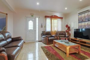a living room with leather furniture and a flat screen tv at Wonder House in Feteiras