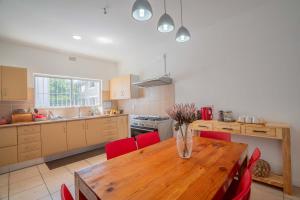 cocina con mesa de madera y sillas rojas en The Avenue House en Ciudad del Cabo