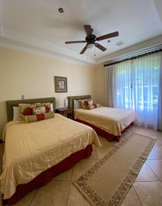 1 dormitorio con 2 camas y ventilador de techo en Pacific Sun en Jacó