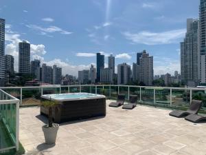 a rooftop patio with a hot tub and chairs on a city skyline at 7a in Panama City