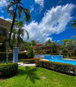 un complejo con piscina y palmeras en Pacific Sun en Jacó