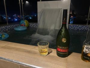 eine Flasche Wein und ein Glas am Pool in der Unterkunft Lujoso jacuzzi privado mi cell 347-864 -3082 in San Francisco de Macorís