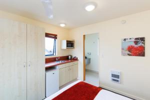 uma cozinha com armários brancos e um tapete vermelho em Bella Vista Motel Palmerston North em Palmerston North