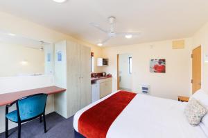 a hotel room with a bed and a kitchen at Bella Vista Motel Palmerston North in Palmerston North