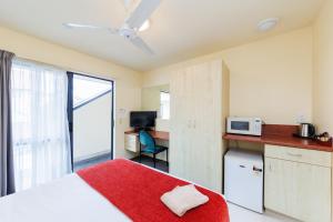 a bedroom with a bed and a kitchen with a microwave at Bella Vista Motel Palmerston North in Palmerston North