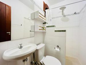 Baño blanco con aseo y lavamanos en Casa da Vila Outeiro das Brisas en Praia do Espelho