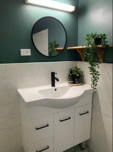 een badkamer met een witte wastafel en een spiegel bij Pet friendly guesthouse with ping pong in Sydney