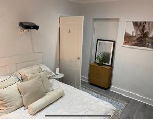 um quarto com uma cama com lençóis brancos e almofadas em Central Private Double Bedroom in a 2bedroom Apartment, connected via underground, overground and many bus routes em Londres