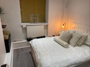 Un dormitorio con una cama blanca con almohadas y una ventana en Central Private Double Bedroom in a 2bedroom Apartment, connected via underground, overground and many bus routes, en Londres