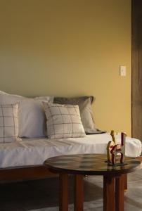 a bed with white pillows and a table in a room at Las Marias 21 in San Salvador de Jujuy