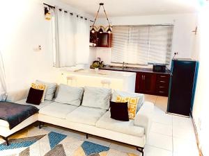 sala de estar con sofá blanco y cocina en Luxurious apartment with King size bed en Dar es Salaam