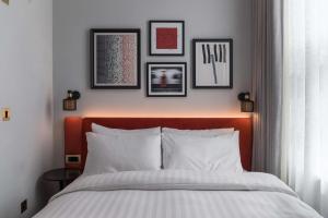 um quarto com uma cama com quatro fotografias na parede em Mornington Hotel London Kensington, BW Premier Collection em Londres