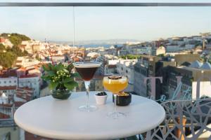 dos copas de vino sentadas en una mesa en un balcón en NH Collection Lisboa Liberdade, en Lisboa