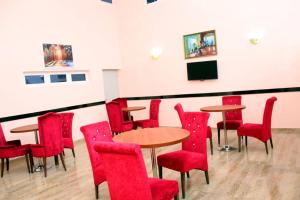 a room with red chairs and tables and a tv at Gregory University Guest House in Lagos