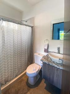 a bathroom with a toilet and a sink and a shower at Brand new apartment, minutes from the beach in Jacó