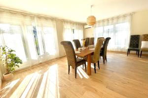 a dining room with a table and chairs and windows at VILLA EDOUARD - 180m2 in nature & forest - 20min Disney - 7min airport in Claye-Souilly