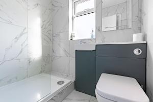 a bathroom with a toilet and a tub and a sink at Tranquil Six Bedroom Haven in Northampton